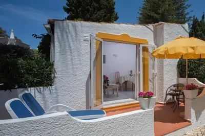 a white building with chairs and an umbrella at 1 Bed Flat - Sleeps 2 - Pool - Parking - Wifi in Luz