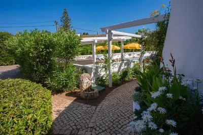 a garden with a stone walkway and a pergola at 1 Bed Flat - Sleeps 2 - Pool - Parking - Wifi in Luz