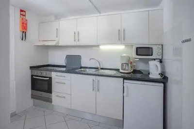 a kitchen with white cabinets and a sink and a microwave at 1 Bed Flat - Sleeps 2 - Pool - Parking - Wifi in Luz