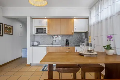 a kitchen with a wooden table with chairs and a dining room at Casa Anaim by Homie in Porto Santo