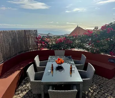 a table and chairs on a balcony with flowers at Casa dos Arrifes - Villa with Ocean view and private Garden in Funchal