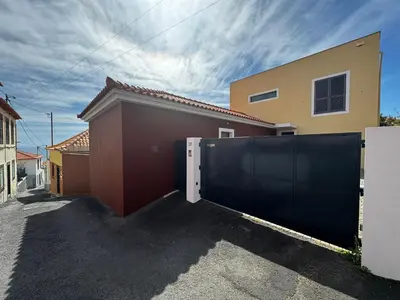 a garage with a black gate in front of a house at Casa dos Arrifes - Villa with Ocean view and private Garden in Funchal