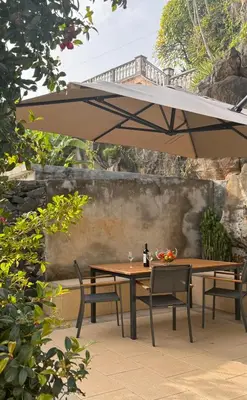 a table and two chairs under an umbrella at Casa dos Arrifes - Villa with Ocean view and private Garden in Funchal