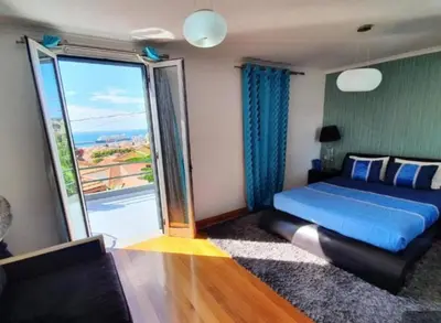 a bedroom with a blue bed and a large window at O farol do funchal in Funchal