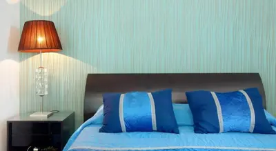 a bedroom with a bed with blue pillows and a lamp at O farol do funchal in Funchal