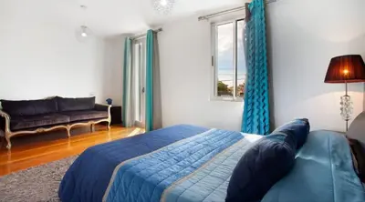 a bedroom with a bed and a couch and a window at O farol do funchal in Funchal