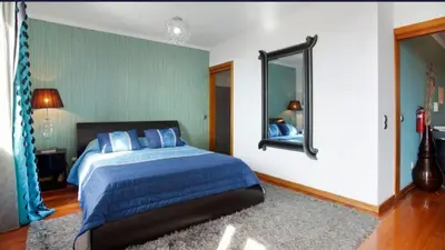 a bedroom with a blue bed and a mirror at O farol do funchal in Funchal