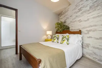 a bedroom with a large bed with a stone wall at Northern Secret by Homie in Ponta Delgada