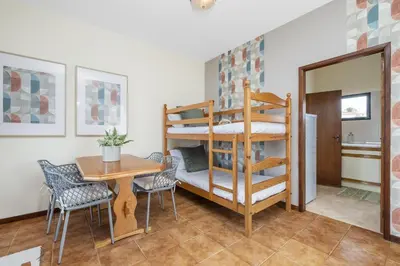 a room with a bunk bed and a table and chairs at Escapadinha do Sol by Homie in Porto Santo