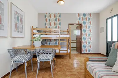 a living room with a table and chairs and a bunk bed at Escapadinha do Sol by Homie in Porto Santo