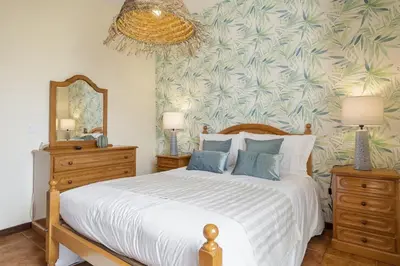a bedroom with a large bed with a tropical wallpaper at Escapadinha do Sol by Homie in Porto Santo