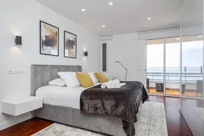 a bedroom with a large bed and a large window at Lido Sunrise Apartment by Homie in Funchal