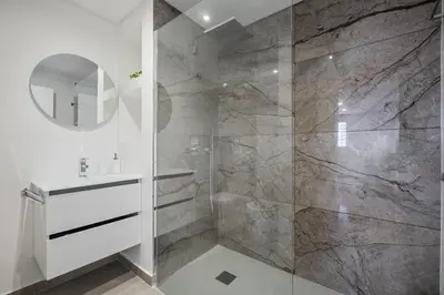 a bathroom with a shower with a sink and a mirror at Lido Sunrise Apartment by Homie in Funchal