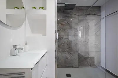 a white bathroom with a shower and a sink at Lido Sunrise Apartment by Homie in Funchal