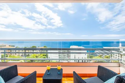 a balcony with chairs and a table and a large window at Lido Sunrise Apartment by Homie in Funchal