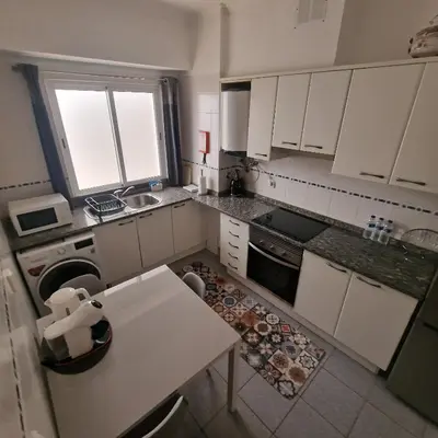 a small kitchen with white cabinets and a table at Ina's Garden in Santa Cruz in Santa Cruz