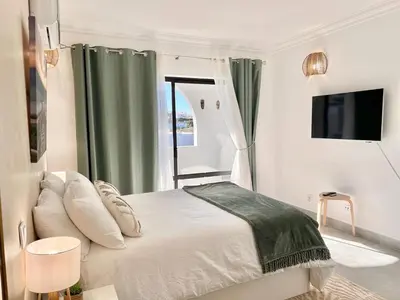 a white bedroom with a bed and a window at Oásis de verão- 2 bedrooms flat with swimming pool in Sagres