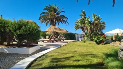 a park with benches and umbrellas and palm trees at RÉSIDENCE LES ARCADES in Almádena