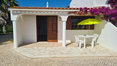 a table and chair with an umbrella in front of a house at RÉSIDENCE LES ARCADES in Almádena