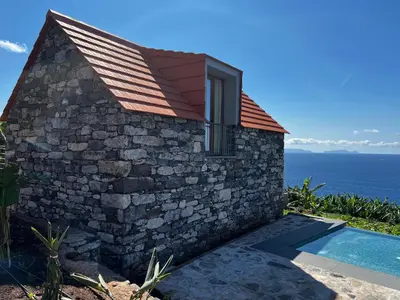 a stone house with a swimming pool next to the ocean at CASAS DO LARANJO- Cottages & Infinity Pool in Gaula