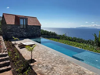 a house with a swimming pool next to the ocean at CASAS DO LARANJO- Cottages & Infinity Pool in Gaula