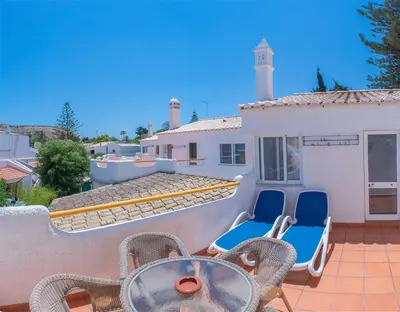 a patio with chairs and a table and a building at Garden T2 Apartment in Luz in Luz