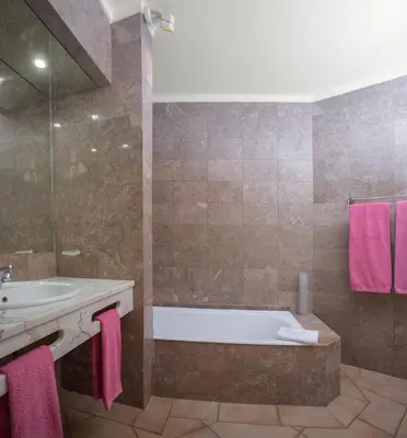 a bathroom with a tub and a sink with pink towels at Garden T2 Apartment in Luz in Luz