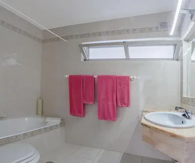 a bathroom with pink towels and a tub and a sink at Garden T2 Apartment in Luz in Luz