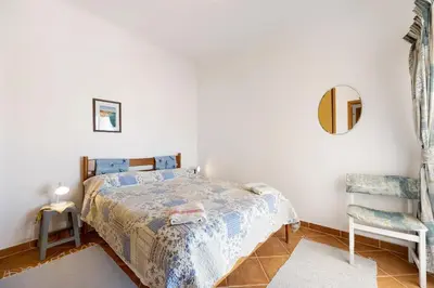 a bedroom with a bed and a chair and a mirror at Casa Do Poço in Budens