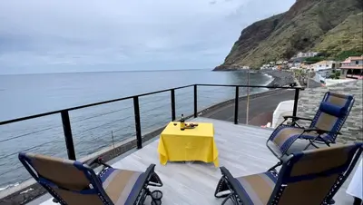 a table and chairs on a deck with the ocean at Ocean Front in Paul do Mar
