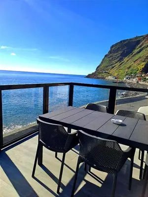a table and chairs on a balcony overlooking the ocean at Ocean Front in Paul do Mar