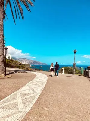 two people walking down a sidewalk near the ocean at Seaview Apartment walking to the Beach in Funchal