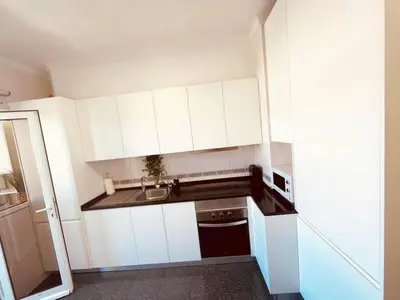 a small kitchen with white cabinets and a sink at Seaview Apartment walking to the Beach in Funchal