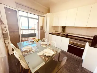 a kitchen with a table and white cabinets and a table and chairs at Seaview Apartment walking to the Beach in Funchal