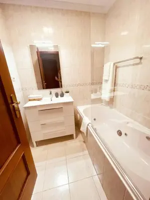 a white bathroom with a tub and a sink at Seaview Apartment walking to the Beach in Funchal