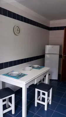 a kitchen with a white table and two stools at Apartamento Capela in Funchal