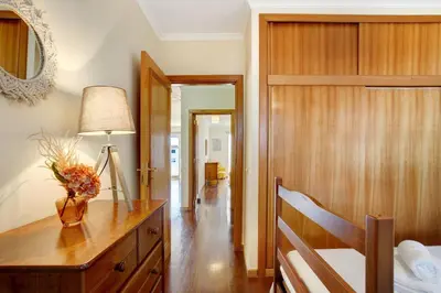 a bedroom with a wooden dresser and a table with a lamp at Apartamento Fénix Garajau in Caniço