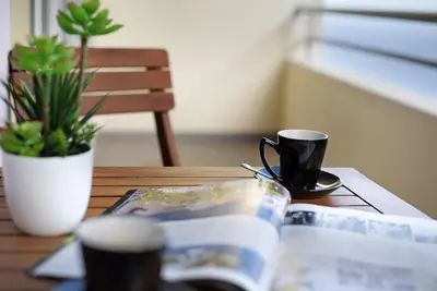 a table with a book and a coffee mug on it at Apartamento Fénix Garajau in Caniço