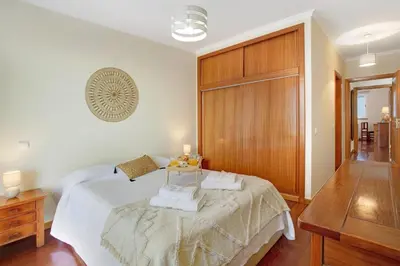 a bedroom with a bed and a desk with a lamp at Apartamento Fénix Garajau in Caniço