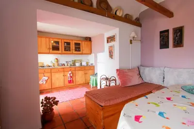 a living room with a bed and a kitchen at Cozy and traditional stone house in Arco da Calheta