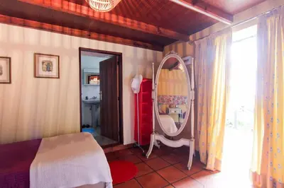 a bedroom with a bed and a mirror in it at Cozy and traditional stone house in Arco da Calheta