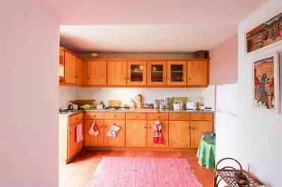 a kitchen with wooden cabinets and a red rug at Cozy and traditional stone house in Arco da Calheta