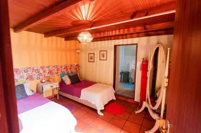 a bedroom with two beds and a mirror at Cozy and traditional stone house in Arco da Calheta