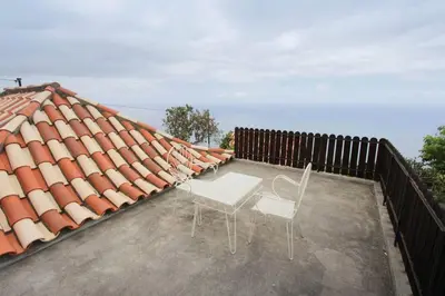 two chairs sitting on the roof of a house at Cozy and traditional stone house in Arco da Calheta