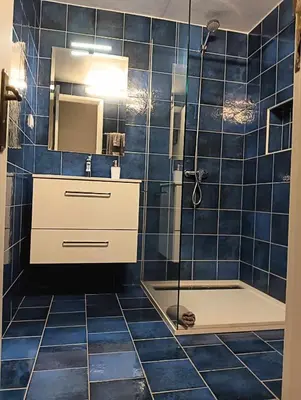 a blue tiled bathroom with a shower and a sink at Maresia's House in Madalena do Mar