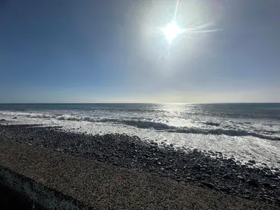 a beach with the sun shining over the ocean at Maresia's House in Madalena do Mar