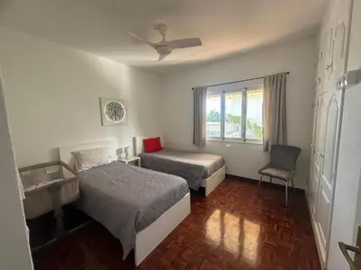 a hotel room with two beds and a chair at Maresia's House in Madalena do Mar