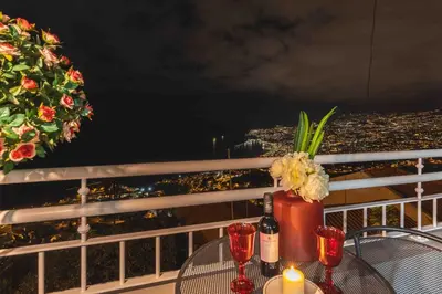 a table with wine glasses and flowers on a balcony at Villa das Furnas in Funchal