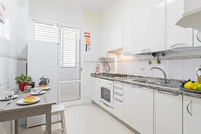 a white kitchen with white cabinets and a table at Achada I by An Island Apart in Funchal