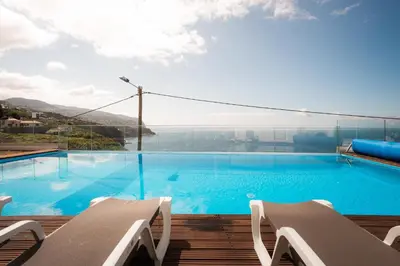 a large swimming pool with a view of the water at Sea View Villa Mar Lindo nr Ponta do Sol in Ponta do Sol